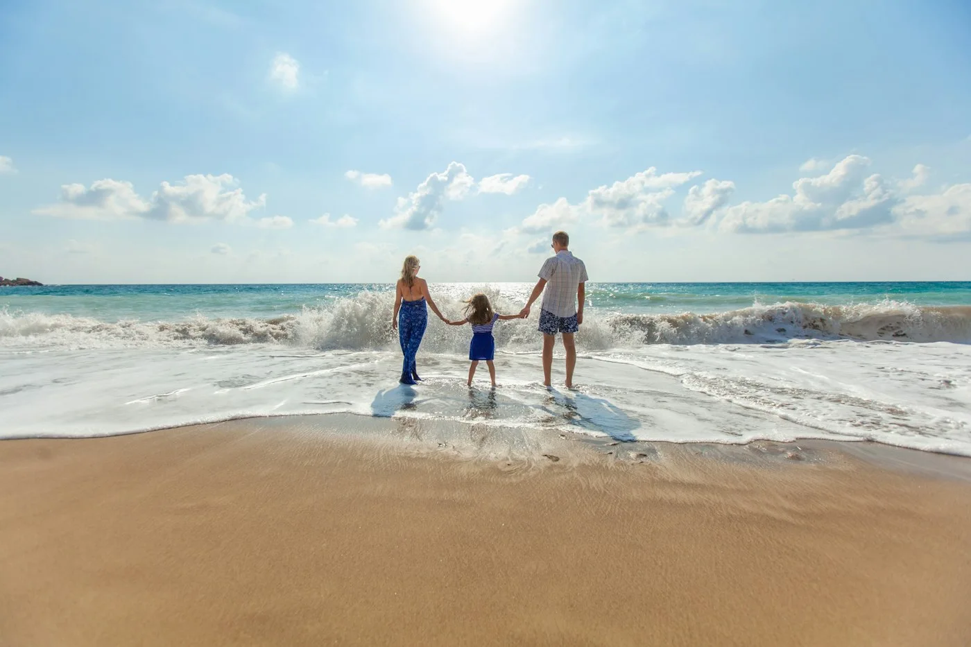 Two adults and one child walking beside the sea