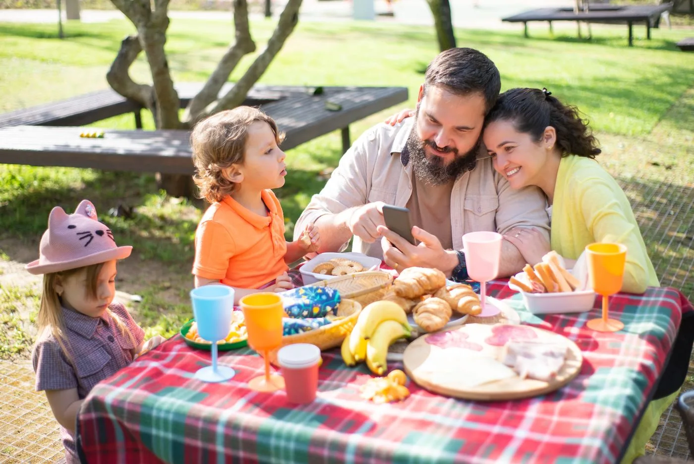 A family enjoying food together on a picnic blanket