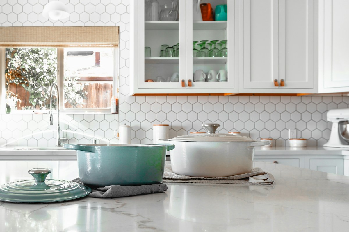 Cooking pots and lids on a bright kitchen counter.