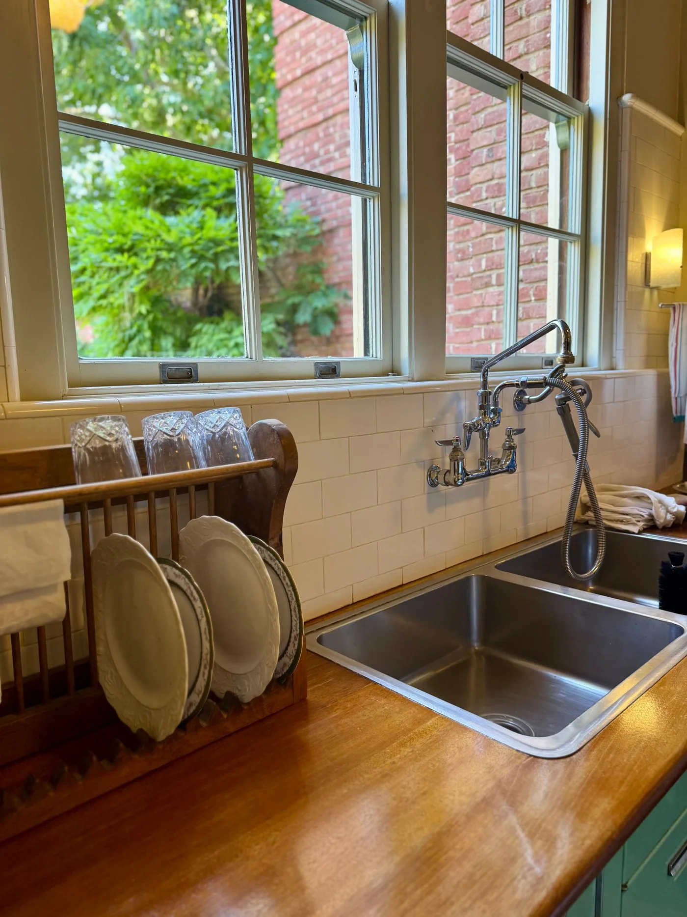A kitchen sink with plates beside a window.