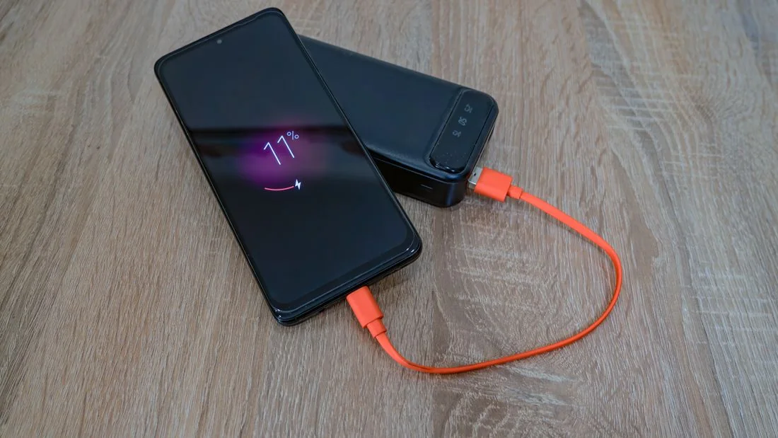 A smartphone connected to a portable power bank.