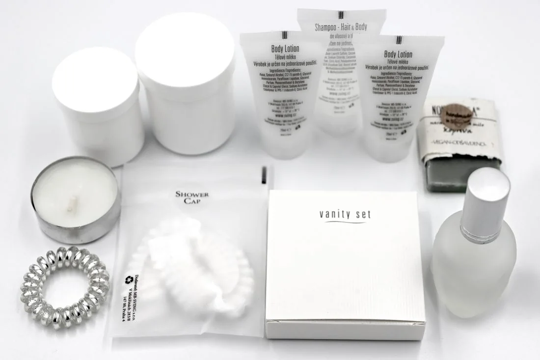 Small labeled toiletries and hotel amenities arranged on a surface.