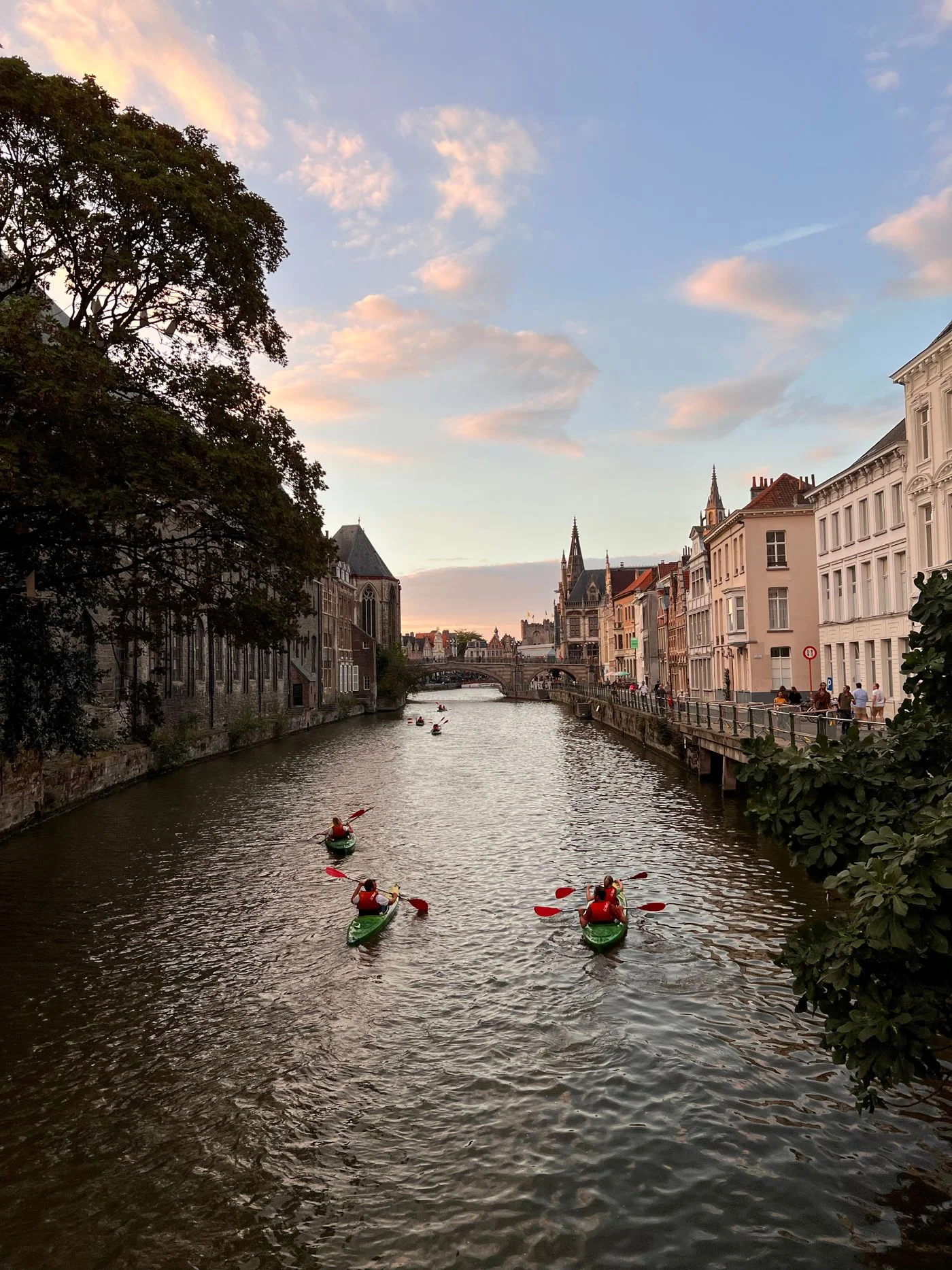 Kayakers on a canal between historic buildings in Ghent.