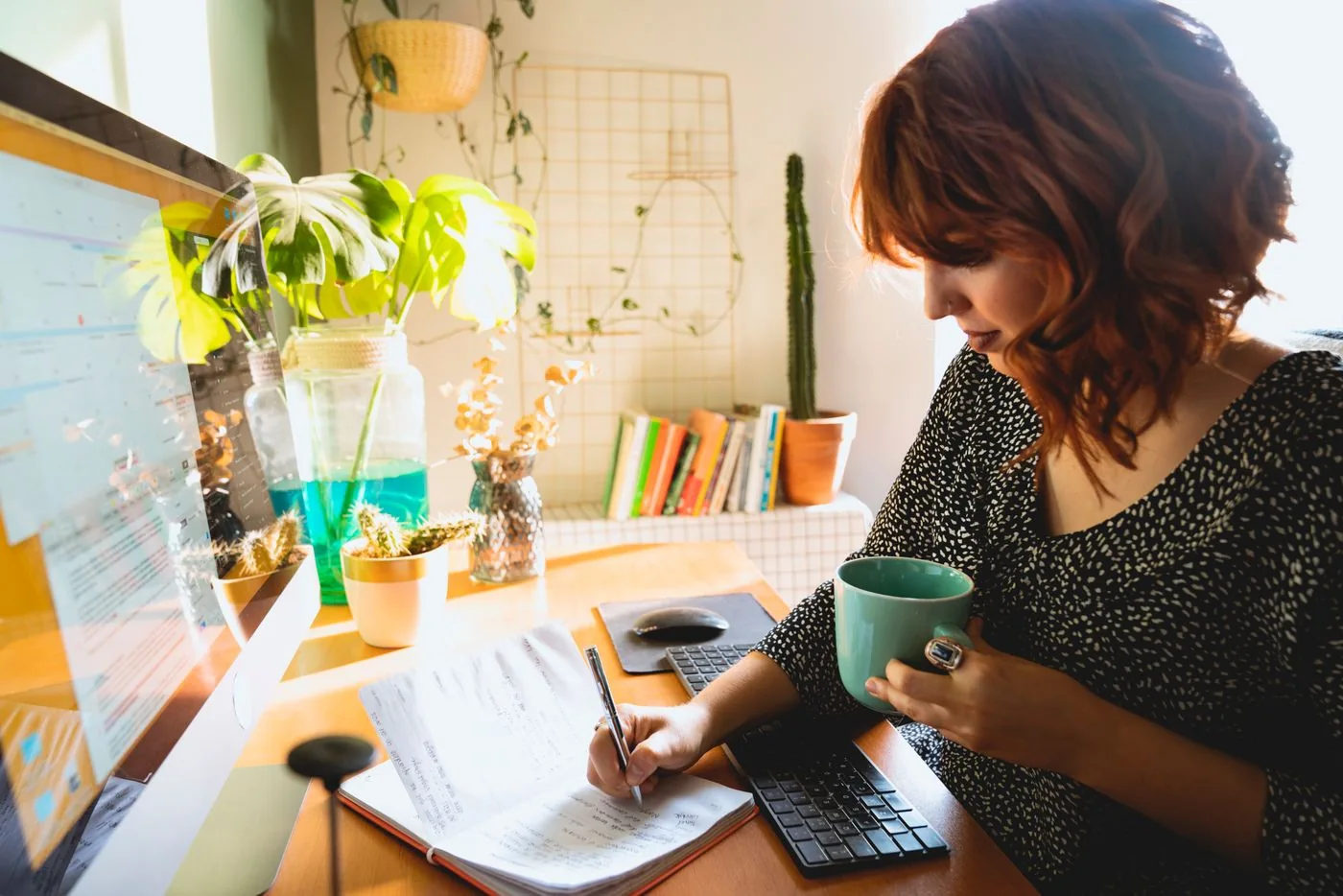 Woman writing at a desk while holding a cup