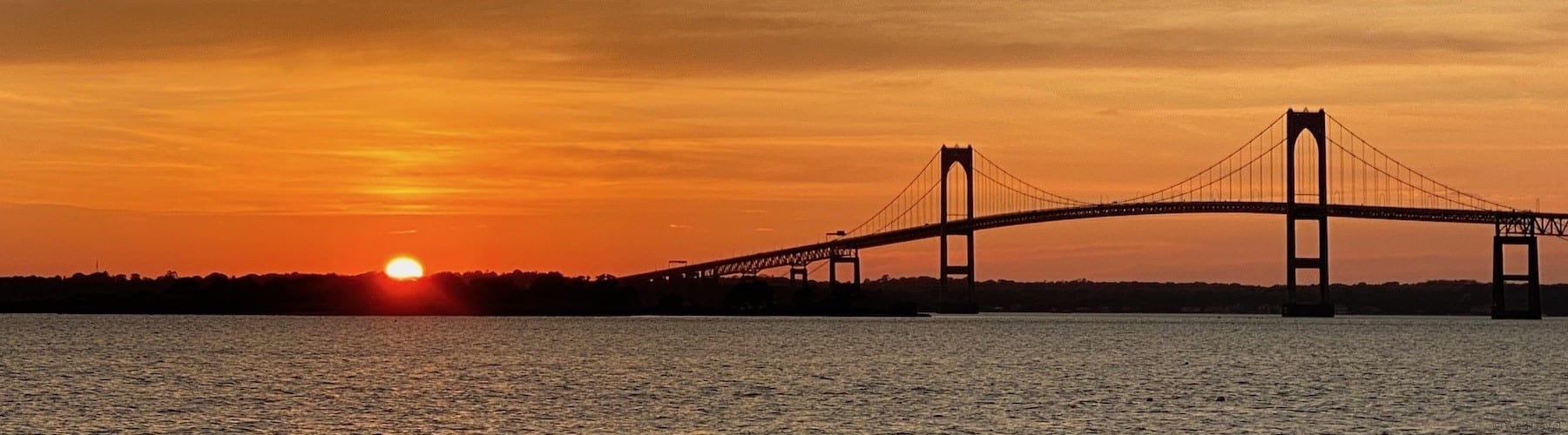 sunsetting behind Newport Pell Bridge