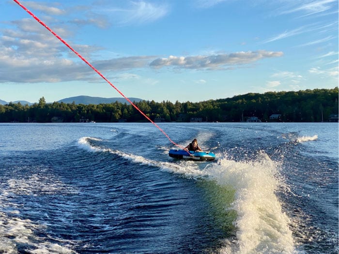 girl being pulled behind a boat on a tube on Lake Placid