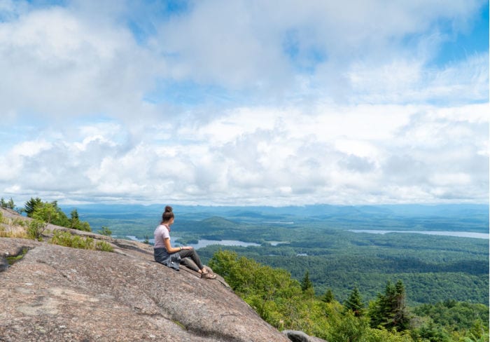 Girl looking out at view at the summit of St Regis Mountain in the Adirondacks