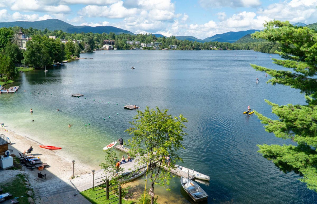 Lake view with trees around and swimmers and paddle boarders on the lake
