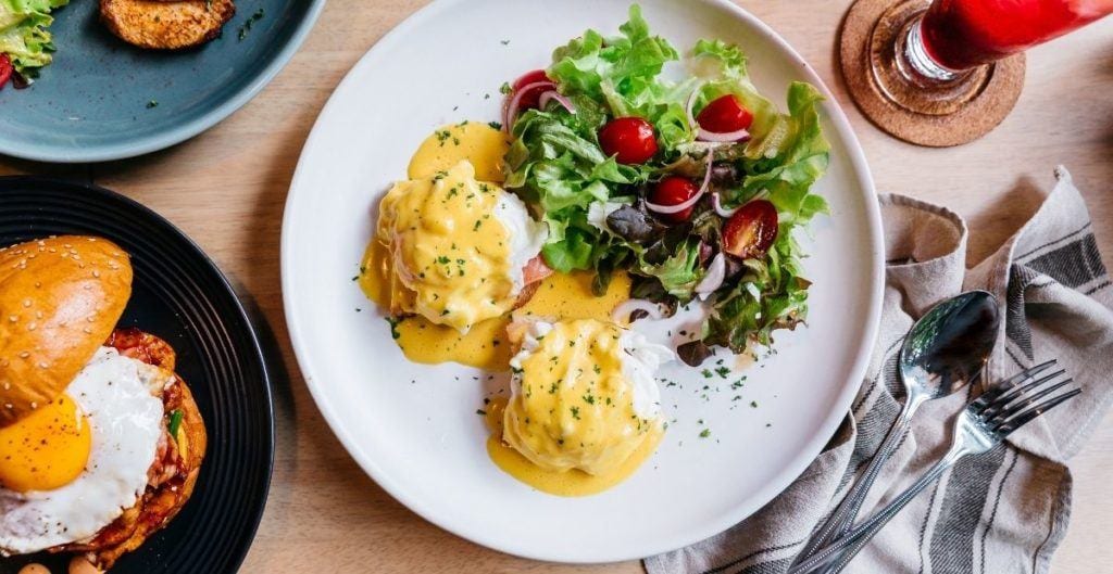 Eggs benedict with salad on plate