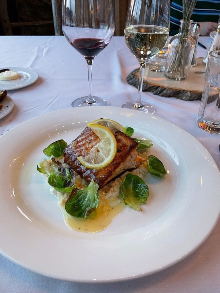 Salmon with lemon on it and brussels sprouts leaves
