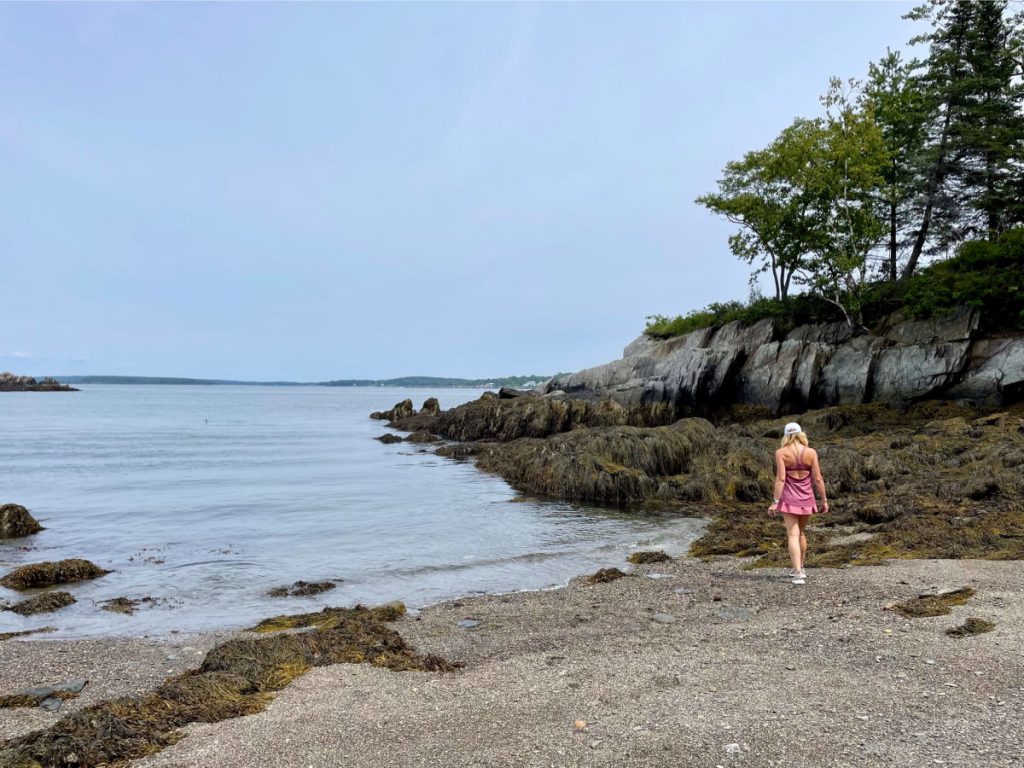 Woman in pink walking on rocky beach