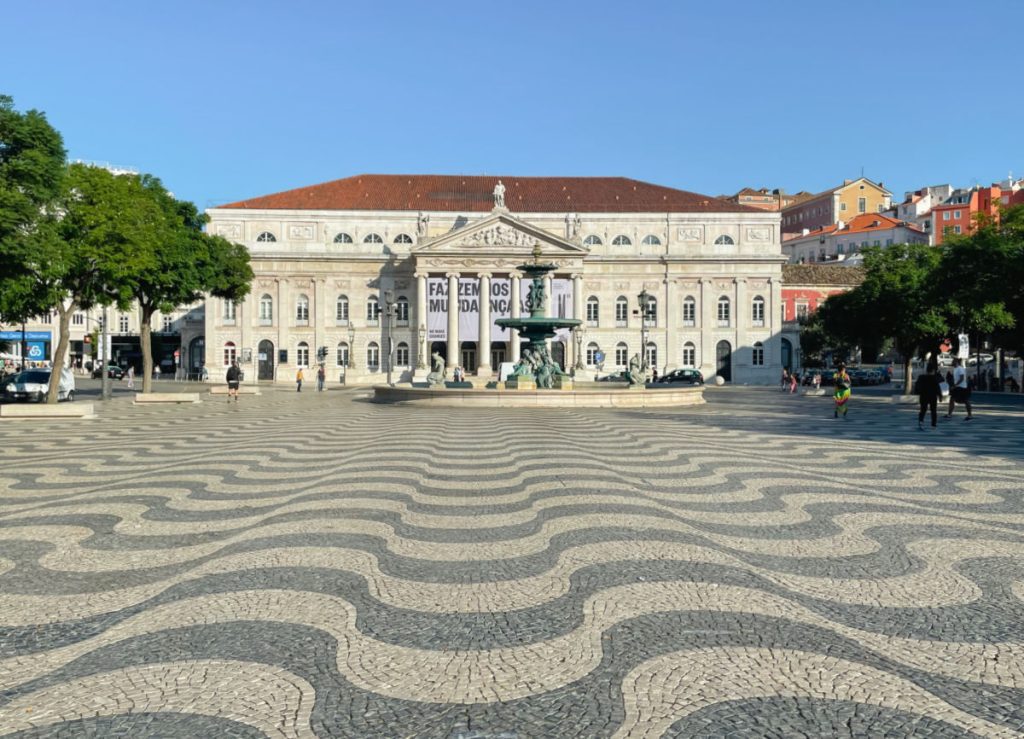 Rossio square in Lisbon with black and white tiles and a fountain in the middle of the square