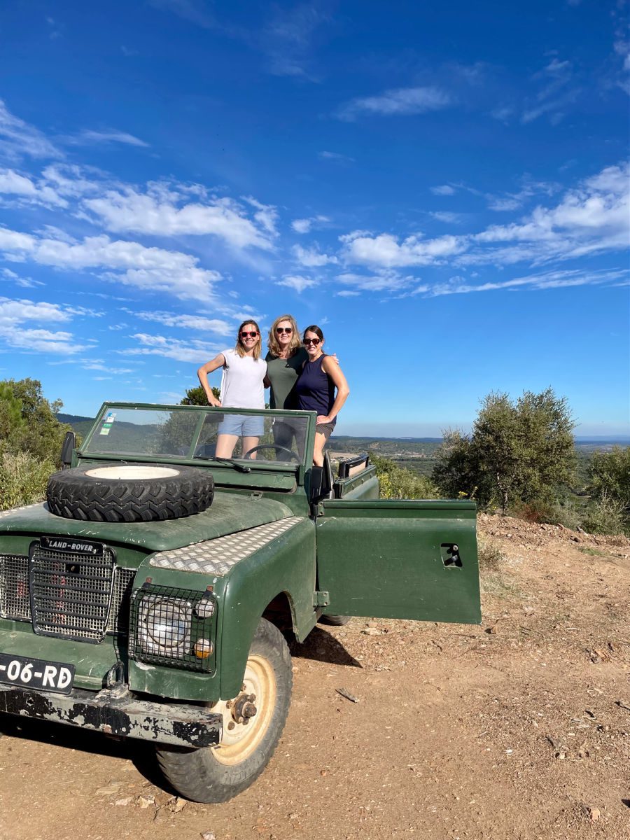3 women standing in the back of a 4x4 jeep 