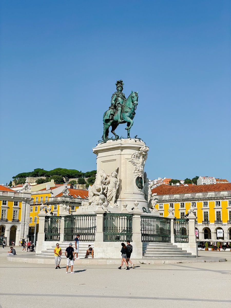 Statue and yellow and white buildings in Commerce Square in Lisbon