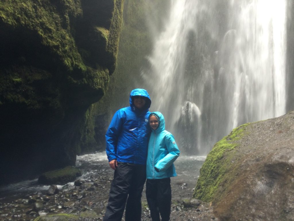Dad and girl in rain jackets by a waterfall