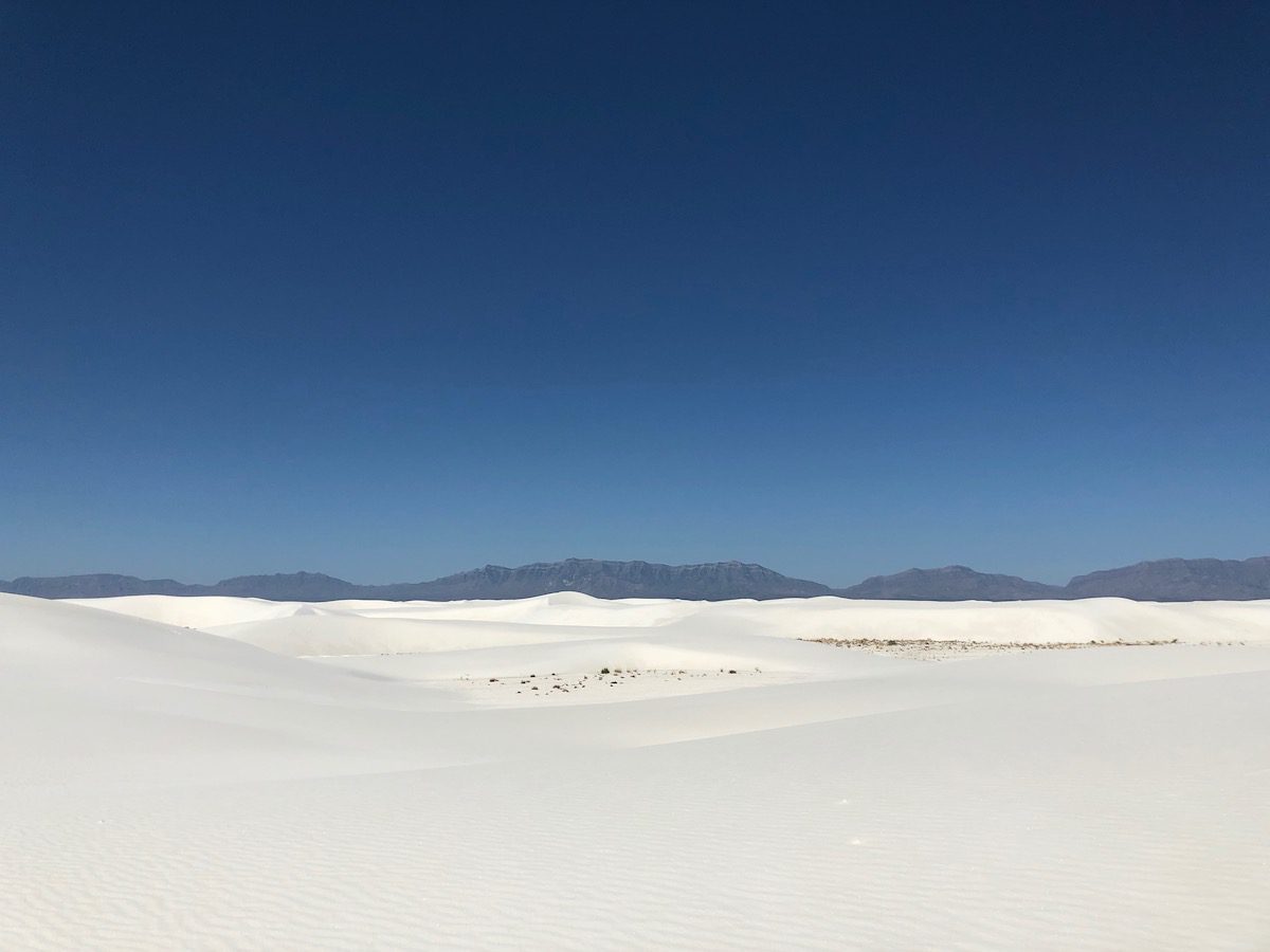 White sand dunes with mountains in the background