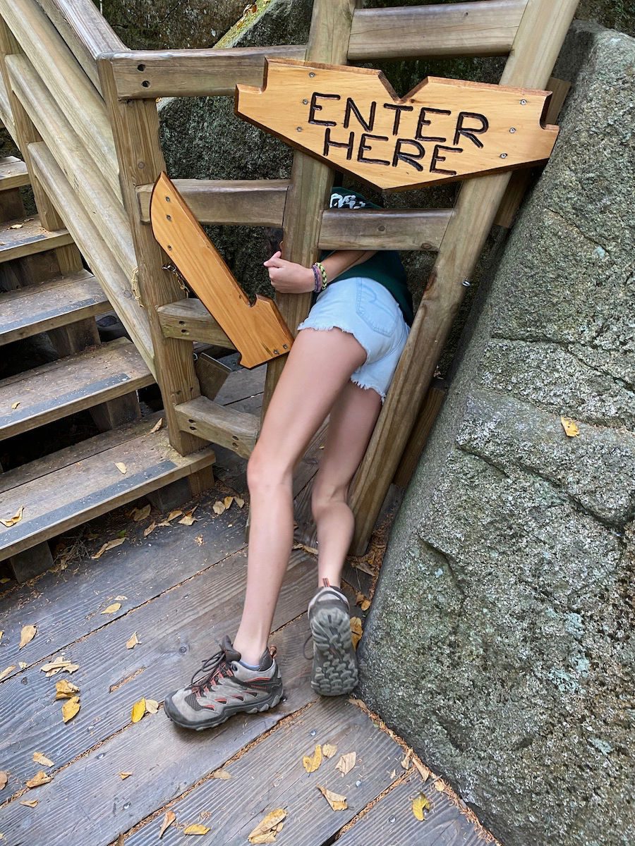 Girl squeezing into Lost River Gorge cave