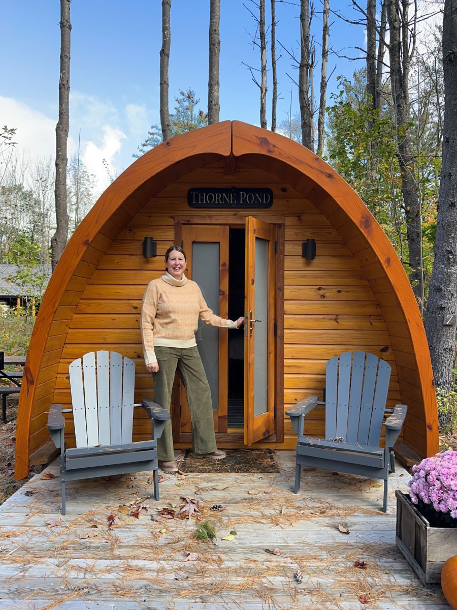 Tamara opening door of Thorne Pond cabin at Alpine Garden Glamping
