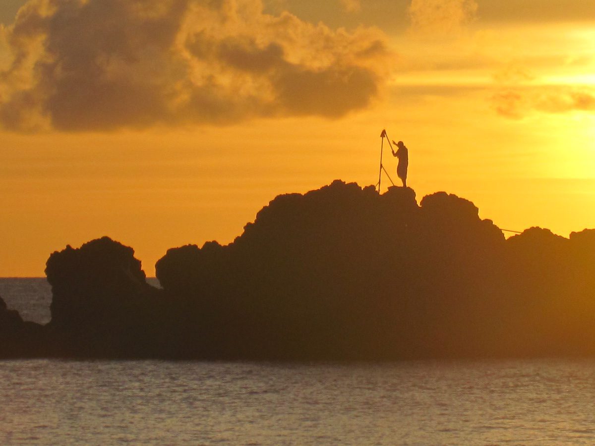 lighting torch at sunset on Black Rock on Maui