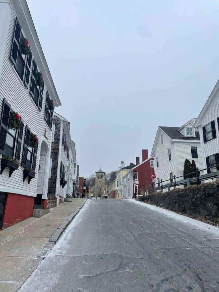 Uphill street lined with colorful houses and a church at the end