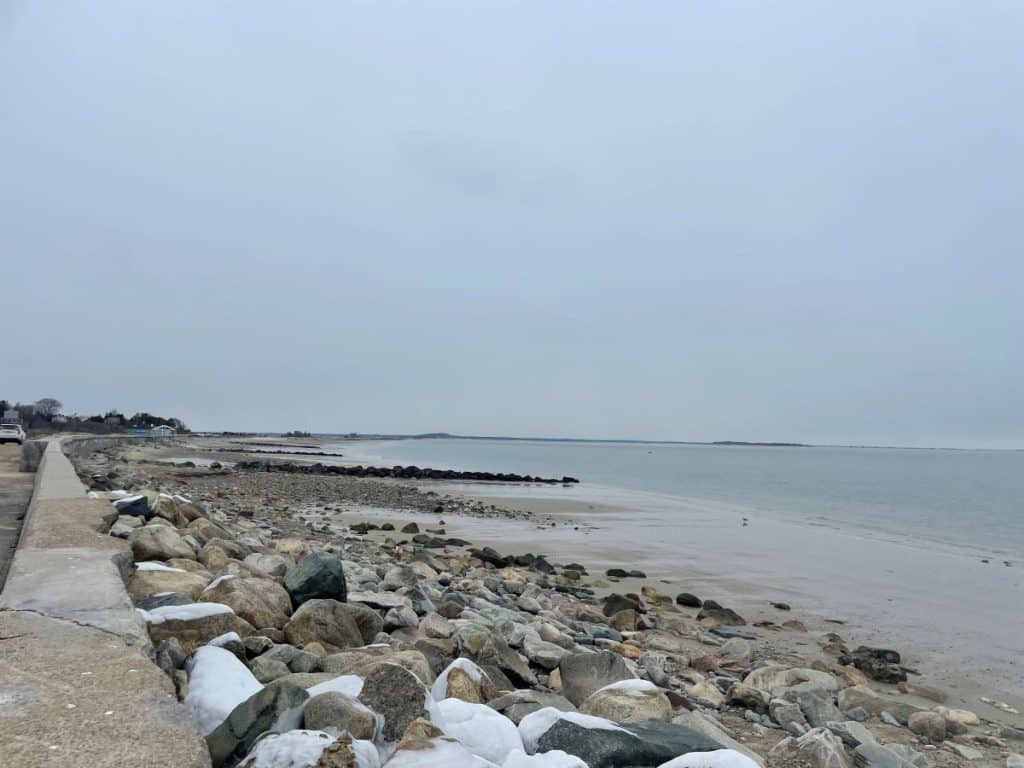 Rocky beach with snow and grey blue sky