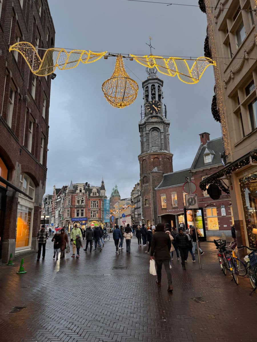 Holiday lights over street with clock tower in background in Amsterdam