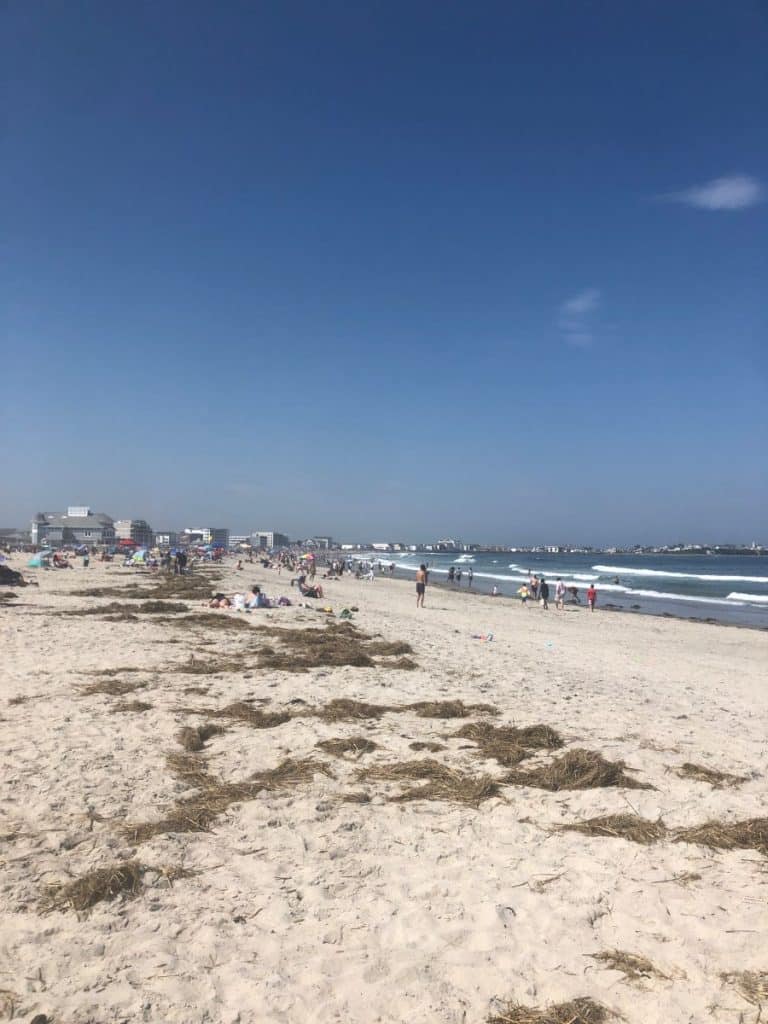 people sitting and walking on the beach during a sunny day