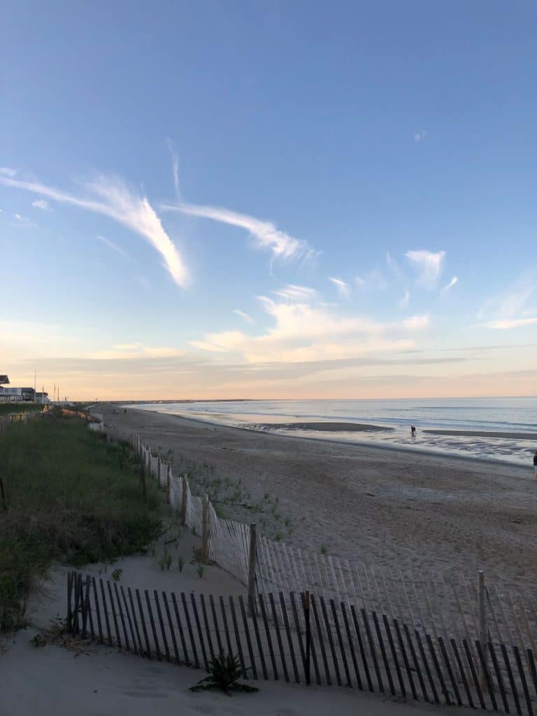 Long sandy beach next to sea grass at sunset