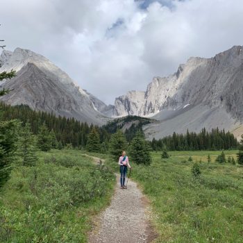 Girl on hiking path with mountains in the background